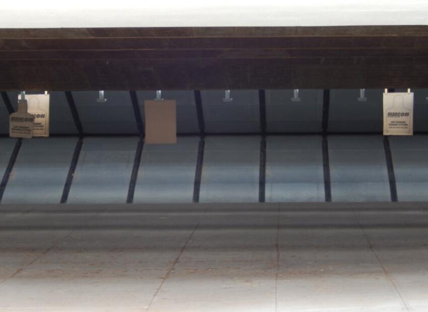 Indoor shooting range with three hanging paper targets.