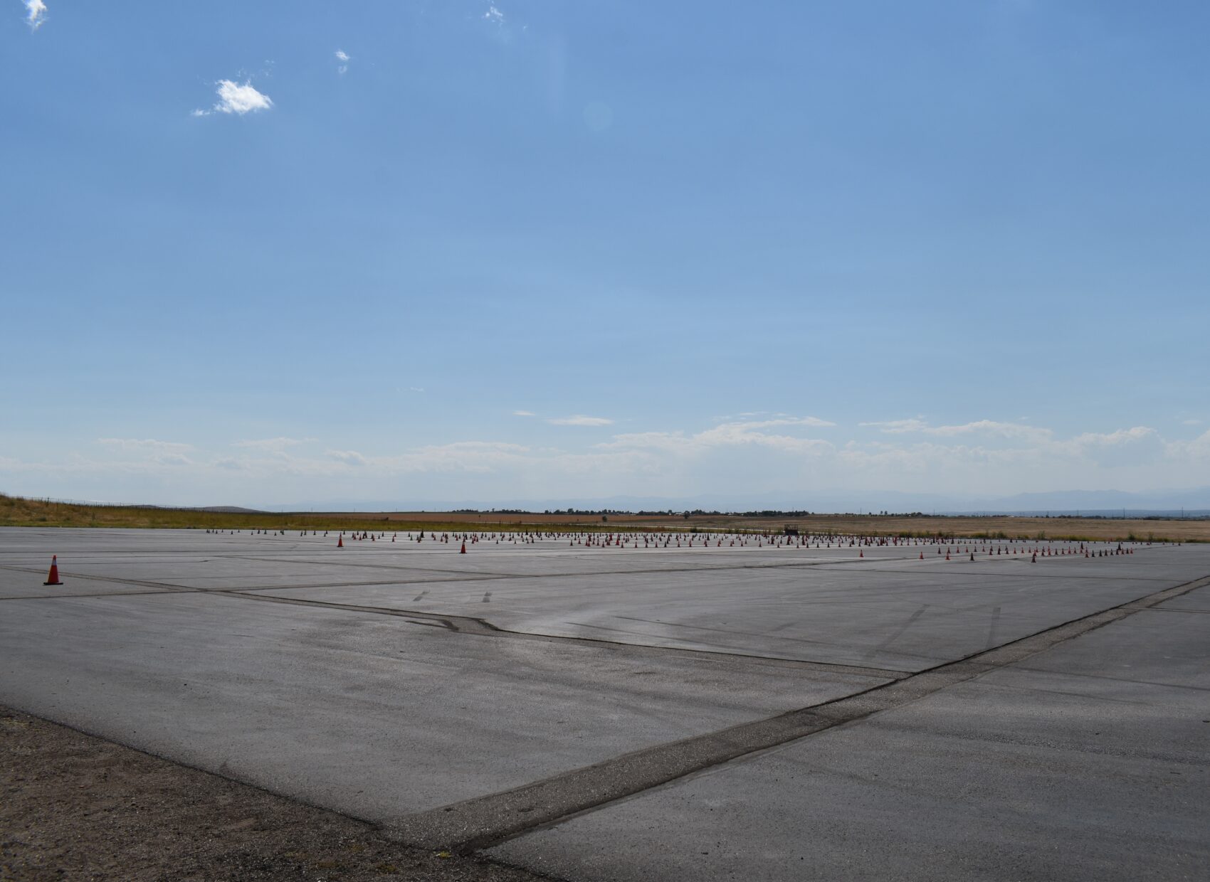 Vast open tarmac with scattered traffic cones under clear blue sky