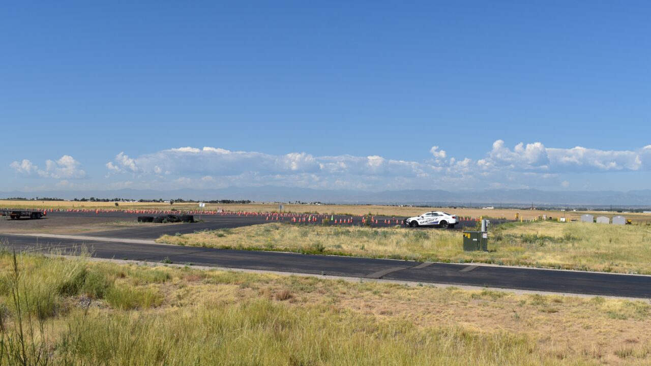 Sheriff car on rural road near traffic cones and mountains in the background